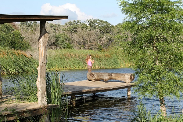 A little girl fishing at Moby Dick's Private Pond Fishing in Cedar Creek, Texas.
